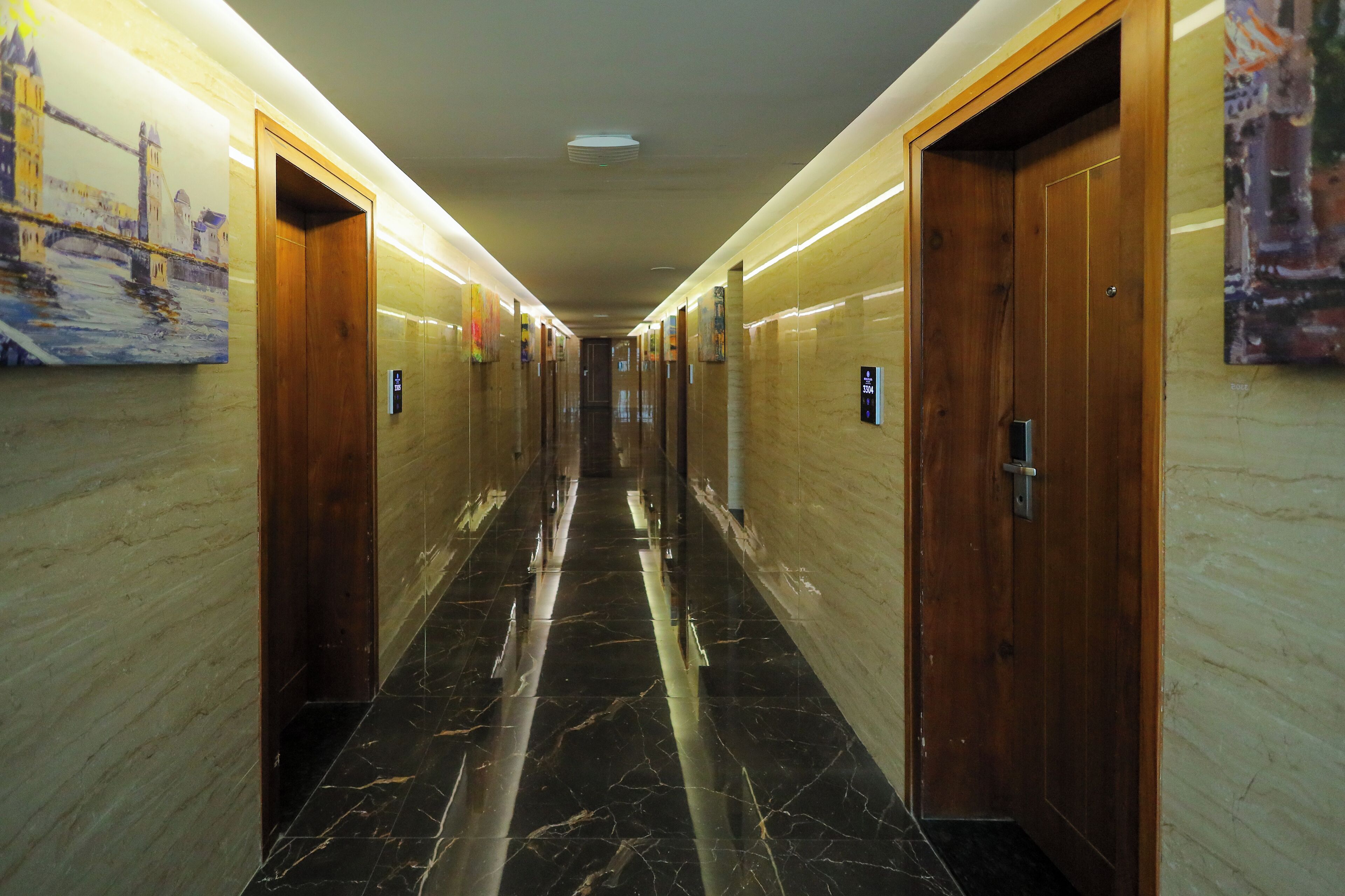 Corredor com pisos de mármore, portas de madeira e um quadro de uma ponte.