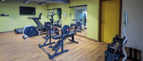 Un gimnasio con máquinas de cardio, equipo de levantamiento de pesas y un espejo.