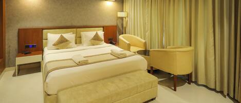 A hotel room with a large bed, a bedside table, a chair, and a lamp.