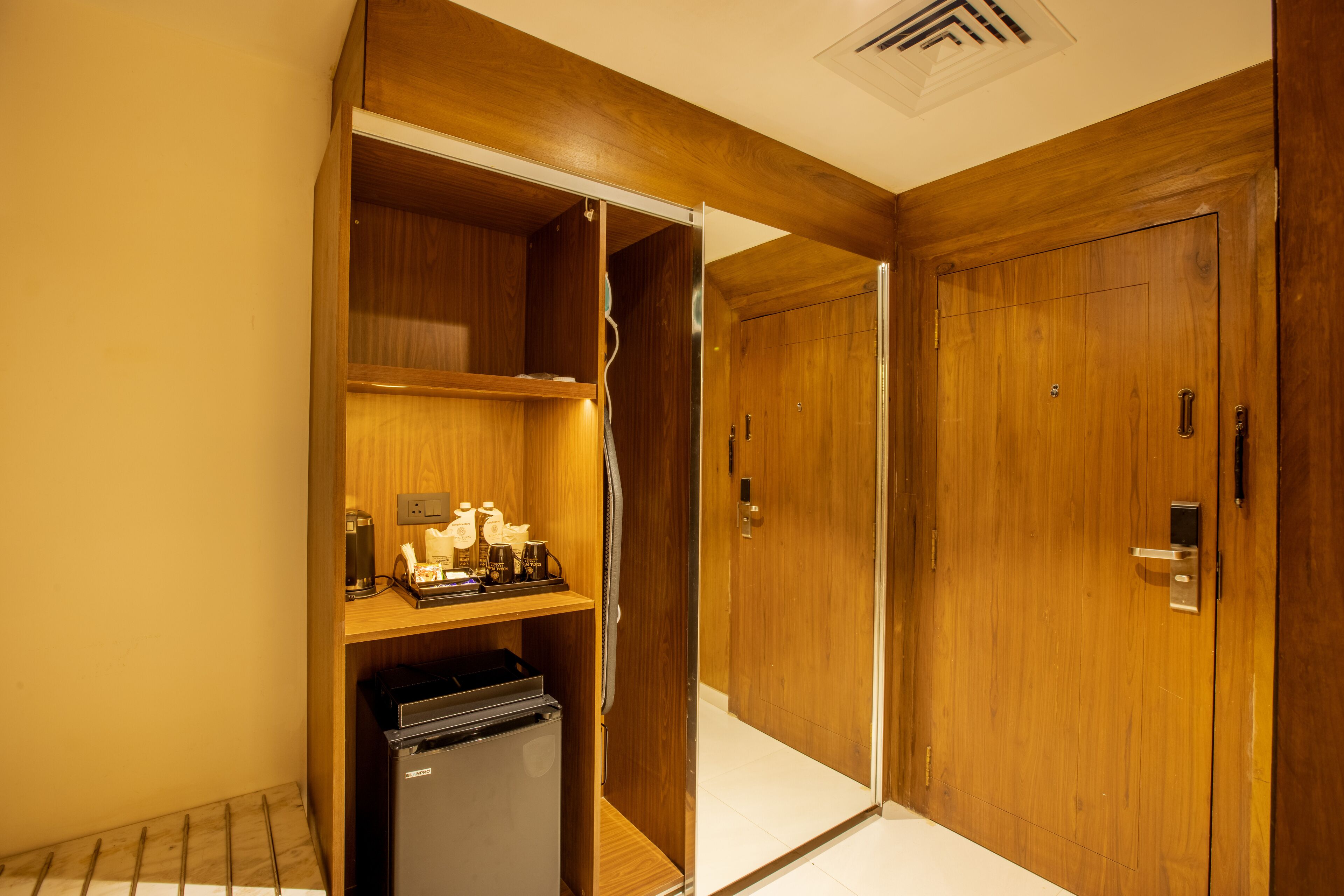 A hotel room with wooden doors, a minibar, and a small refrigerator.