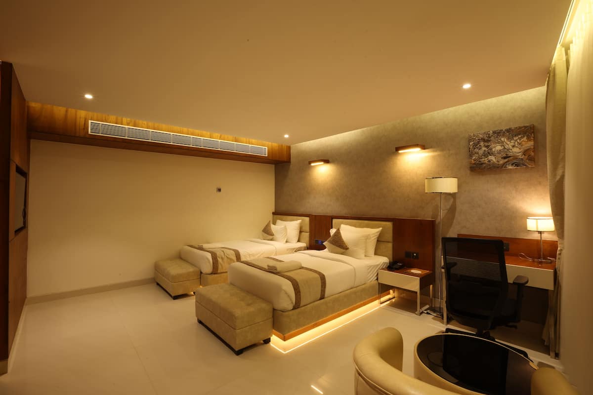 A hotel room with two beds, a desk, a chair, and a desk lamp.