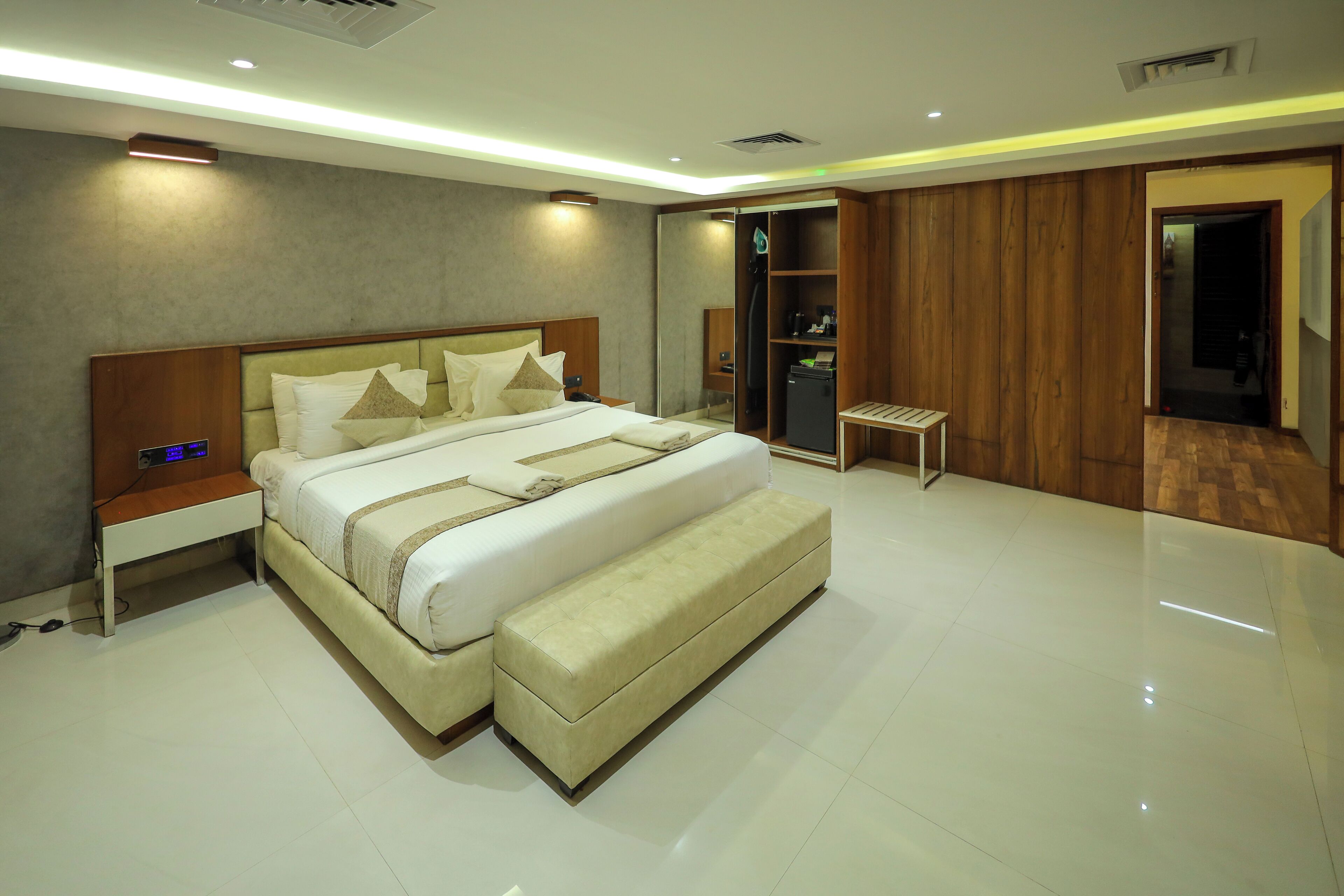 A modern bedroom with a large bed, bedside tables, a wardrobe, and a small table.