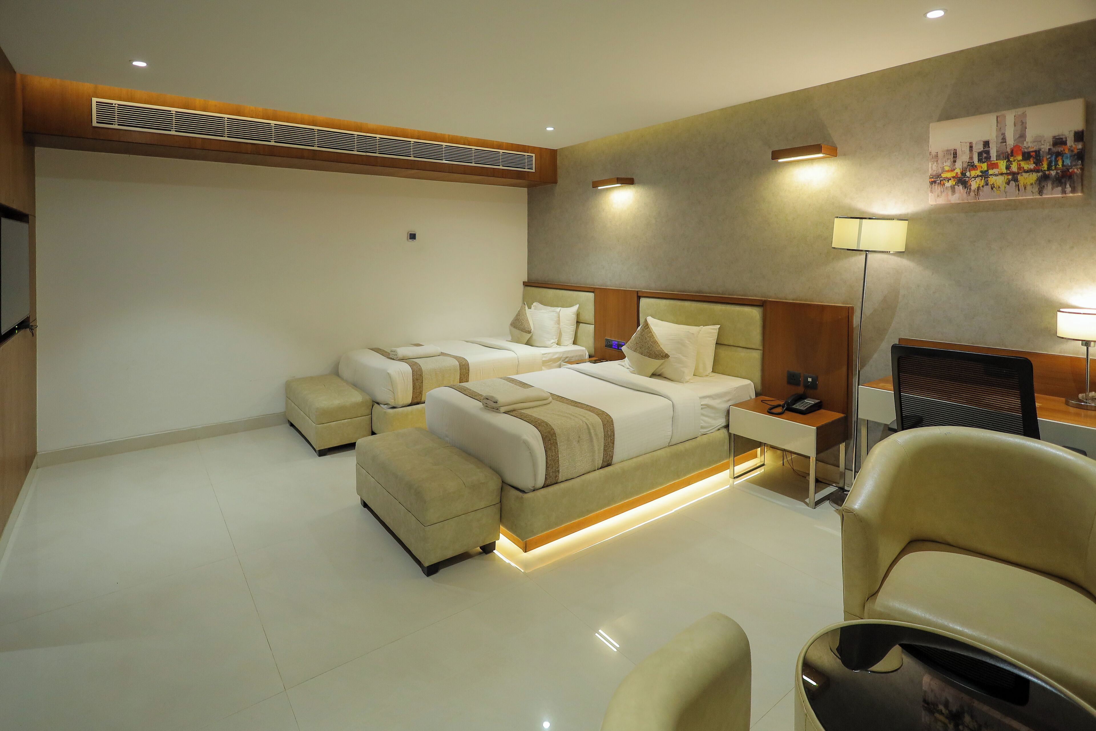 Habitación de hotel con dos camas, un escritorio, una silla y un televisor.
