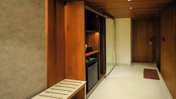 Un pasillo con un banco de madera, un refrigerador empotrado y una puerta al final.