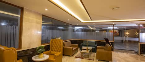 A modern lobby with leather seating, a round table, and a large mirror.