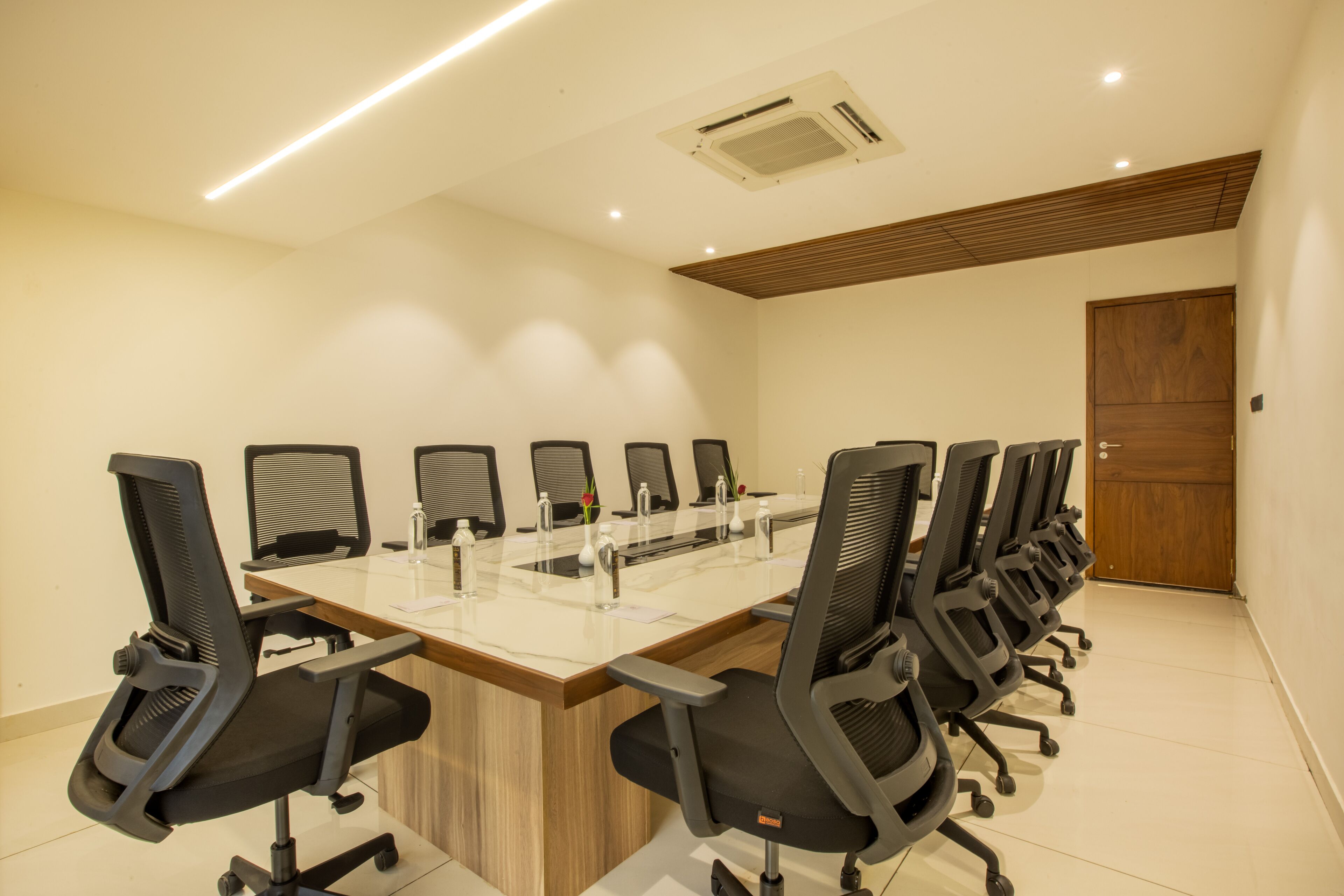 A conference room with a long table, multiple chairs, and a wooden door.