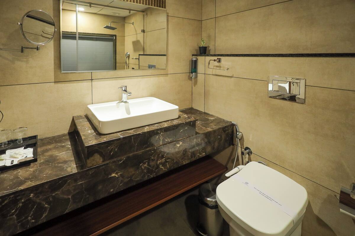 A modern bathroom with a white sink, marble countertop, and a large mirror.