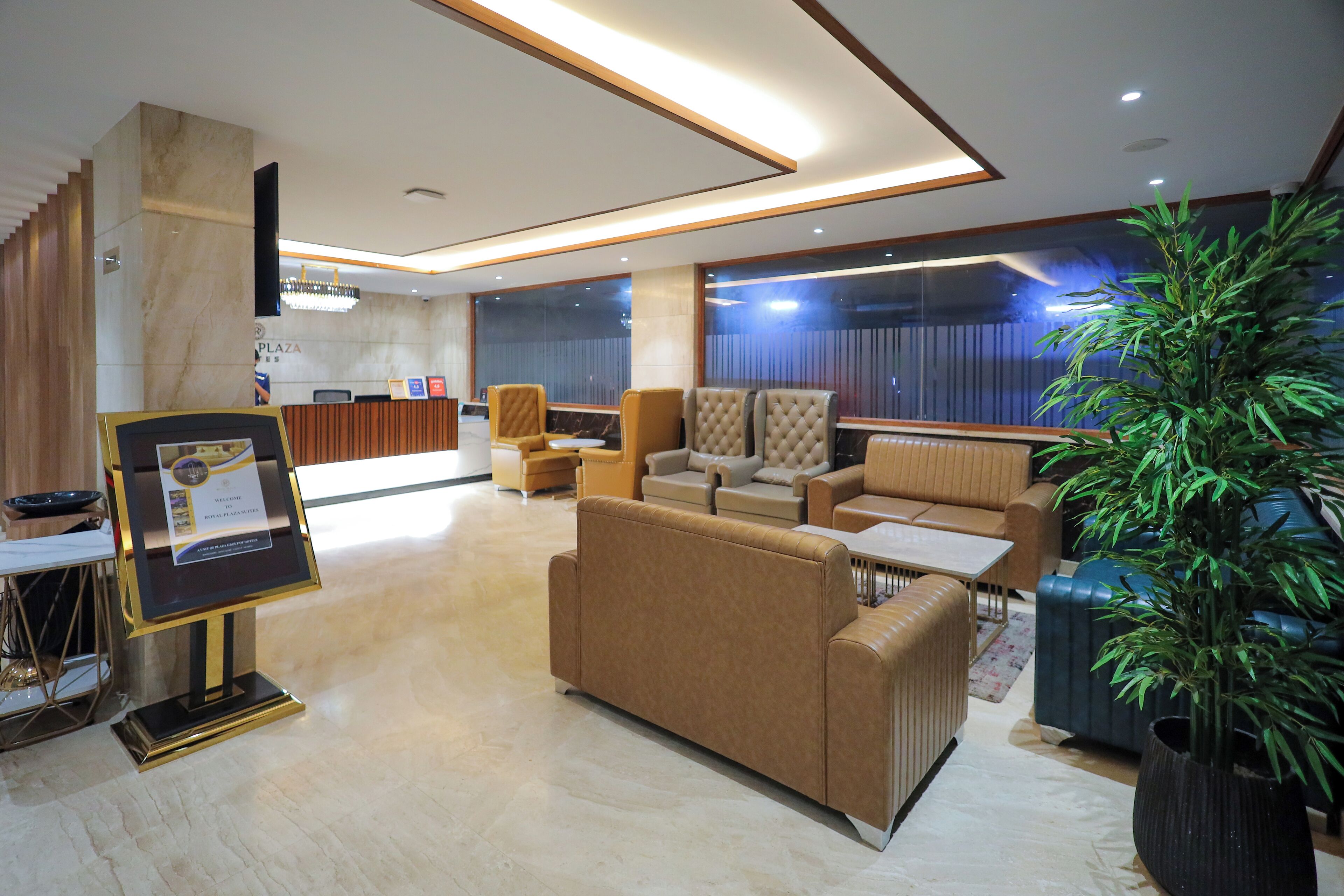 A modern lobby with a reception desk, seating area, and a large potted plant.