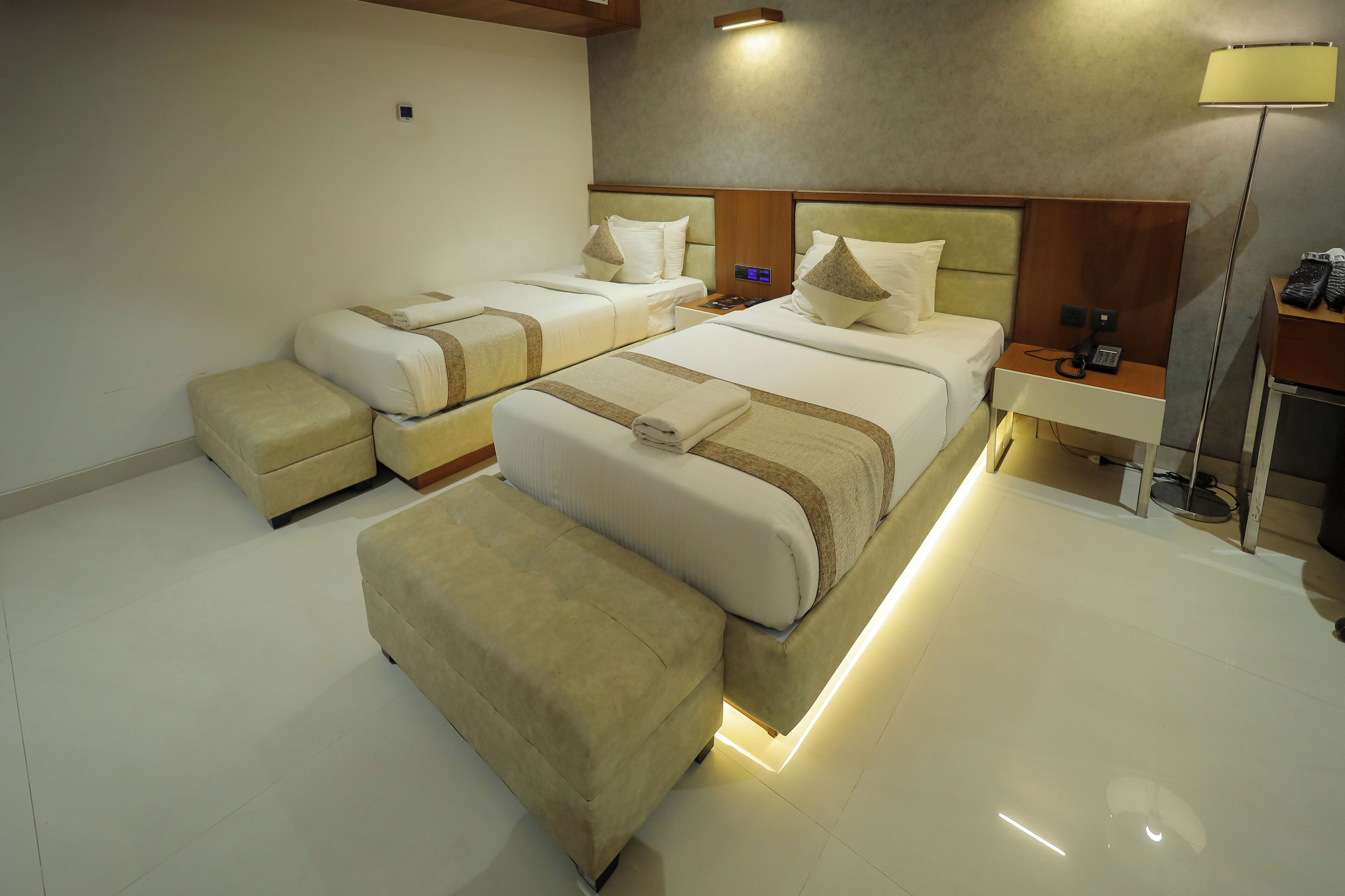 Una habitación de hotel con dos camas, una mesita de noche con un teléfono y una lámpara.