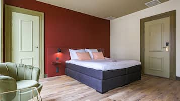 Un dormitorio con cama, mesita de noche, silla y puerta.