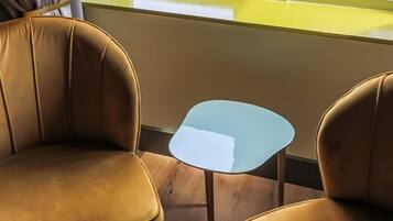 Una esquina de una habitación con dos sillones de cuero marrón y una pequeña mesa cuadrada con cubierta azul claro.