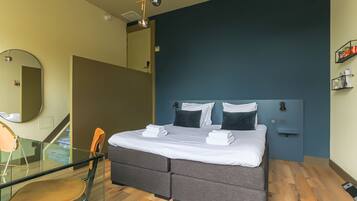 Een moderne slaapkamer met een bed, nachtkastjes, een spiegel en een glazen tafel met een stoel.