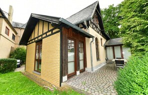 Une maison traditionnelle à colombages, avec une façade en briques, un toit en tuiles et une cour pavée.