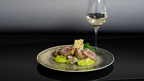 En tallrik mat tillsammans med ett glas vitt vin, placerat på en reflekterande yta.