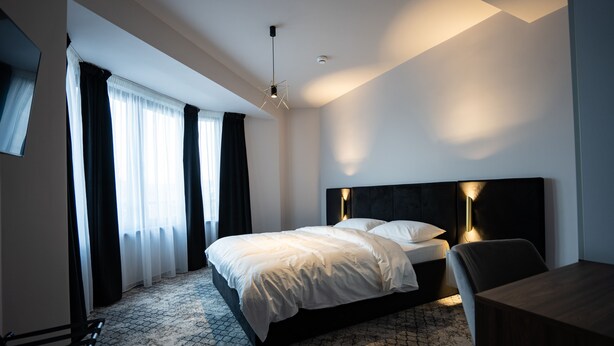 Ett modernt hotellrum med en stor säng, ett skrivbord och en stol.