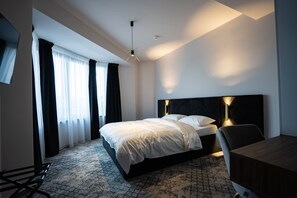 Une chambre d’hôtel moderne, dotée d’un grand lit, d’un bureau et d’une chaise.