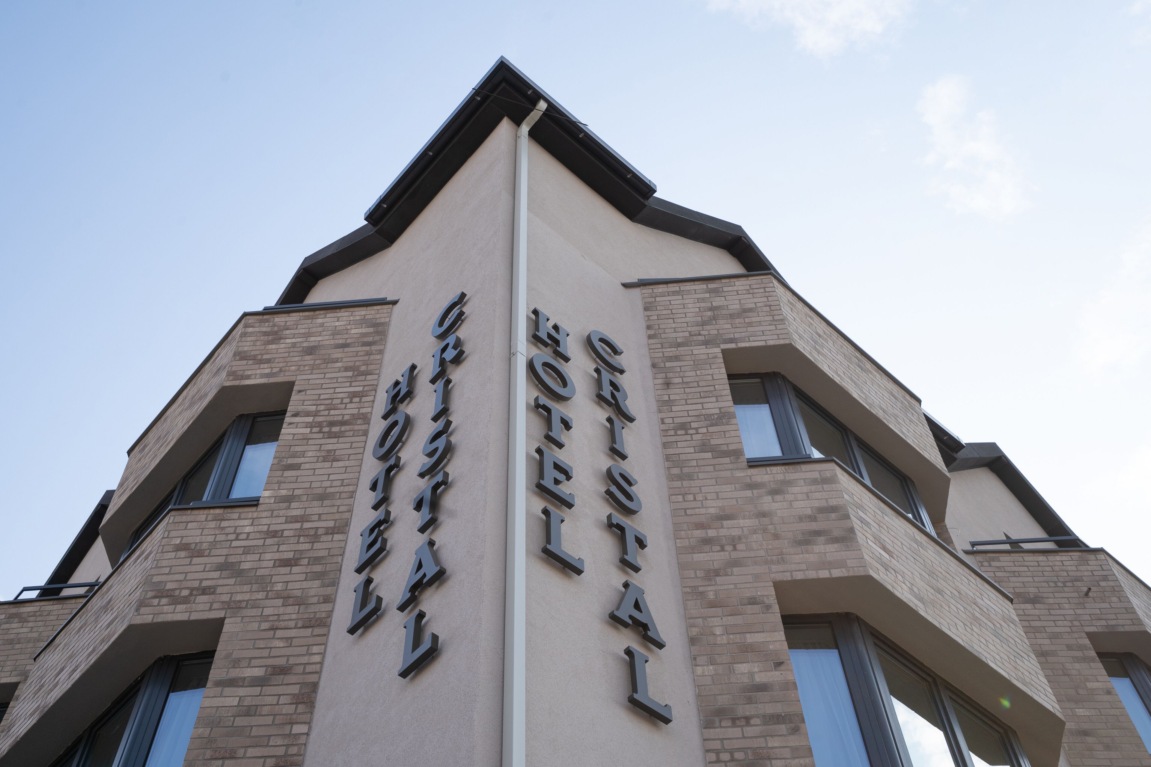 A hotel with a modern architectural design, featuring a prominent vertical sign with the name 'Crystal Hotel'.