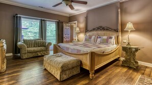 Quarto com cama grande, uma cadeira, uma mesa e um ventilador de teto.