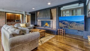 Uma sala de estar moderna com lareira, uma televisão grande e vista para as montanhas.
