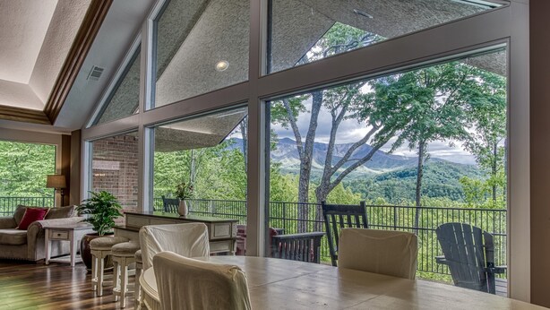 Um quarto espaçoso com uma grande mesa de jantar, assentos confortáveis e vista para uma paisagem exuberante através de janelas amplas.