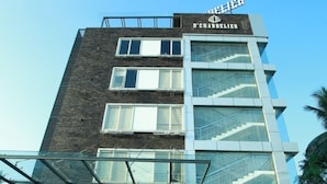 A modern hotel entrance with a glass facade, a staircase leading up to the entrance, and a sign above the door. - DCHANDELIER (Kanayannur)