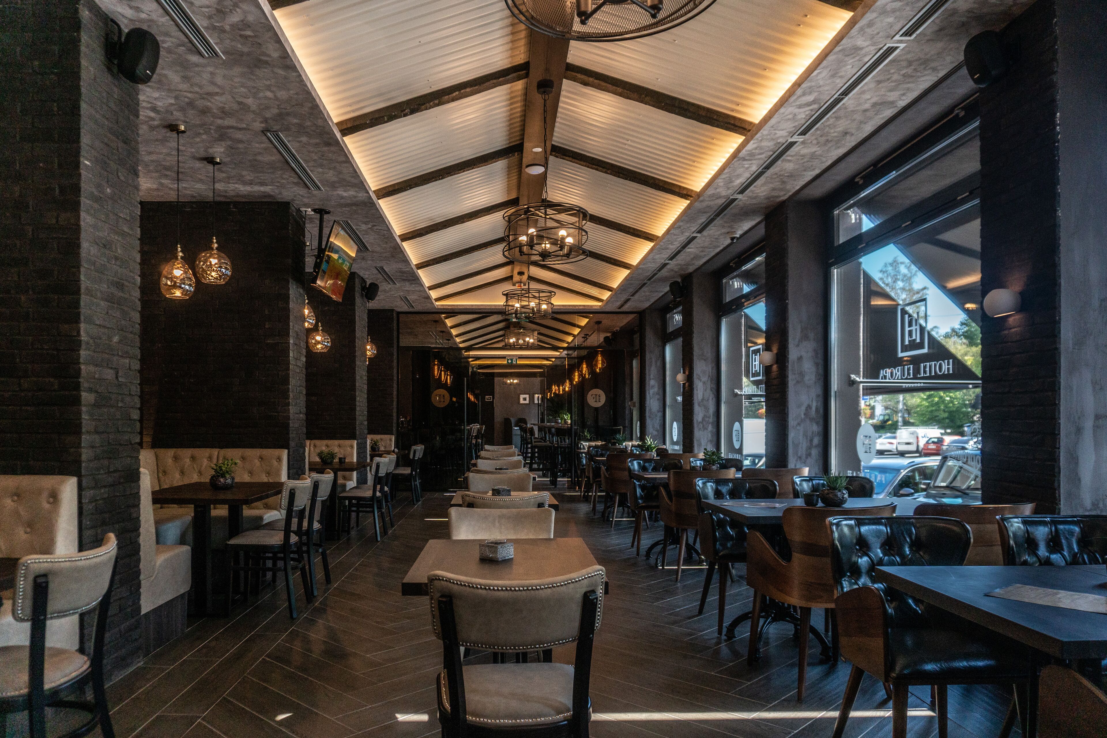 A spacious restaurant with high ceilings, exposed brick walls, and modern lighting fixtures.