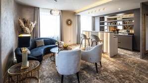 Una sala de estar moderna con un sofá, dos sillones, una mesa de centro y una zona de comedor con barra.