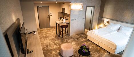Une chambre d’hôtel comprenant un lit, un bureau, une chaise, une petite table avec un vase et un téléviseur.