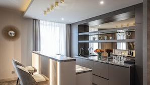 Una cocina moderna con una isla central, taburetes de bar, un lavamanos integrado y un espejo decorativo.
