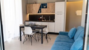 Une cuisine moderne avec des meubles en bois, une table à manger avec des chaises et un canapé bleu dans l’espace salon.