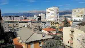 A residential area with multi-story buildings, balconies, and a mountainous backdrop. - Apartment 4 Sleeps 4 Guests (Split)