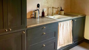 A kitchen with dark cabinetry, a double sink, and two pendant lights. - Rallarhustruns (Hassleholm)