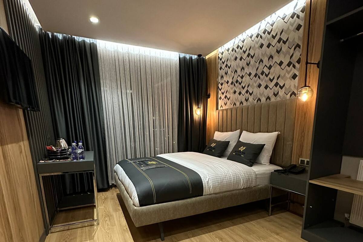 A modern bedroom with a bed, a bedside table, a TV, and a patterned wall.