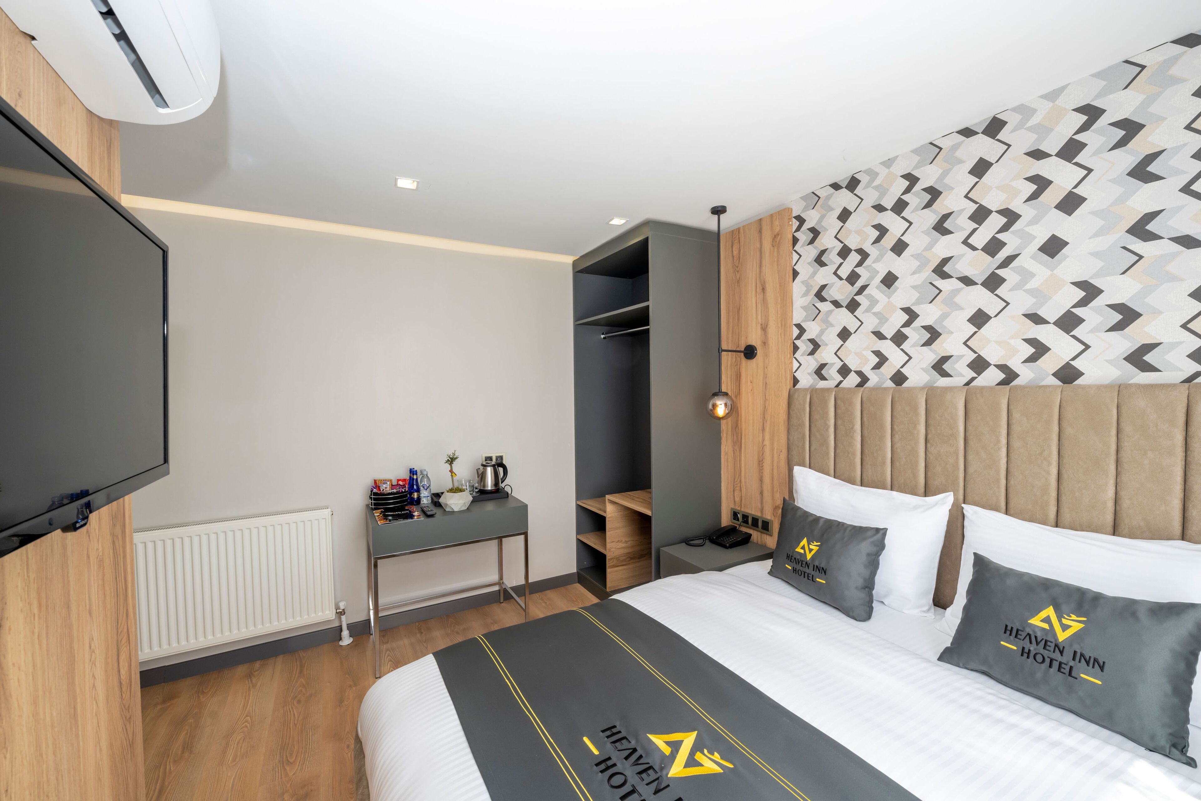 A hotel room with a bed, a desk, a wardrobe, and a television.