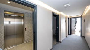 A hallway with an elevator and a door leading to a room. - Heaven Inn Airport Hotel (Arnavutköy)