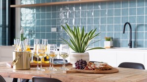 Une table avec des bouteilles de vin, des verres, une plante en pot et une planche de charcuterie.