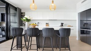 Une cuisine moderne dotée d’un îlot central, de tabourets de bar et de luminaires suspendus.