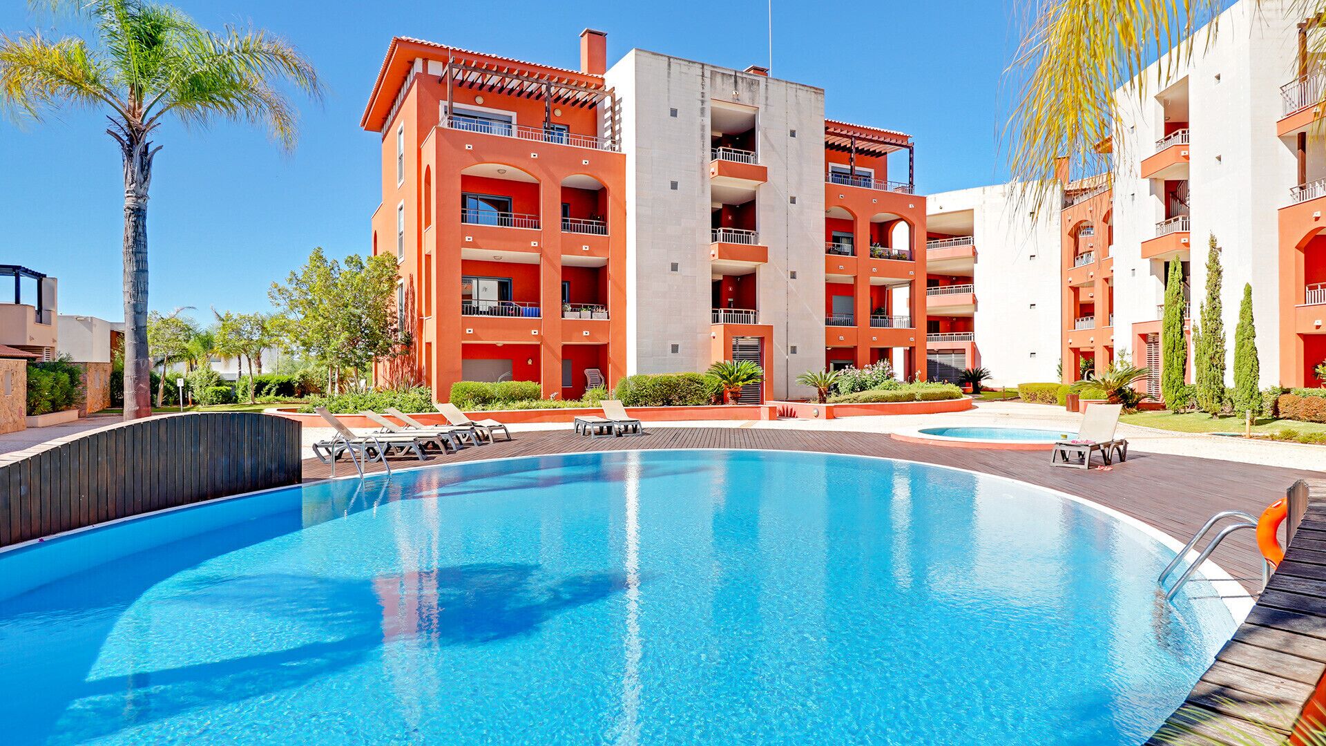A hotel with a large pool, multiple balconies, and a modern architectural design.