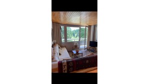 A cozy room with a sofa, a television, and a window offering a view of greenery. - Vars: Very pretty mountain apartment. (Vars)