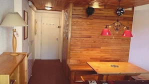 A wooden interior with a table and chairs, a lamp, and a door. - Vars: Very pretty mountain apartment. (Vars)