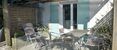 Een terras met een tafel en vier stoelen, een houten hek en een kleine tuin met bloemen.