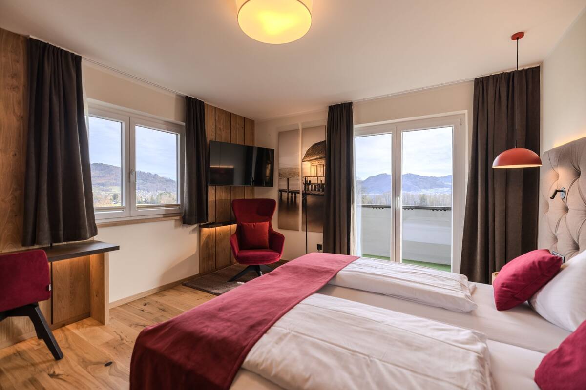 Une chambre d’hôtel avec deux lits, un bureau, une télévision et une vue sur les montagnes.