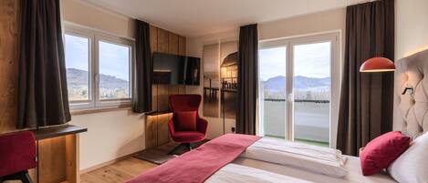 A hotel room with two beds, a desk, a TV, and a view of the mountains.