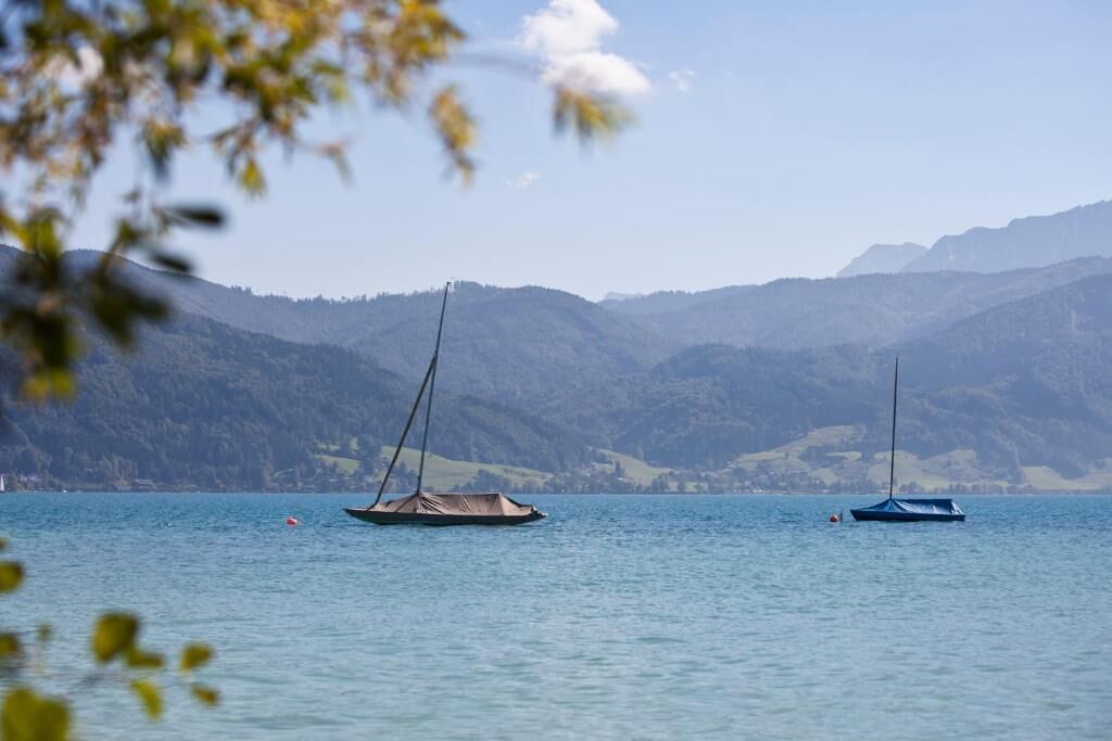 Un lac paisible où flottent deux voiliers, entouré de montagnes.