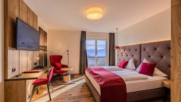 A modern hotel room with a bed, a desk, a chair, a TV, and a large window.