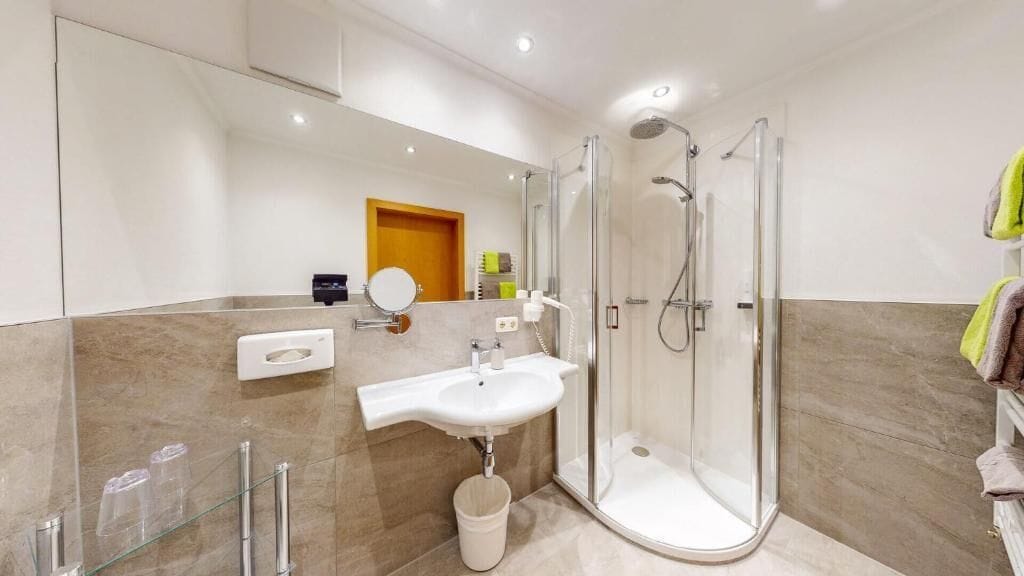 Un bany modern amb dutxa envidriada, un lavabo i un mirall.