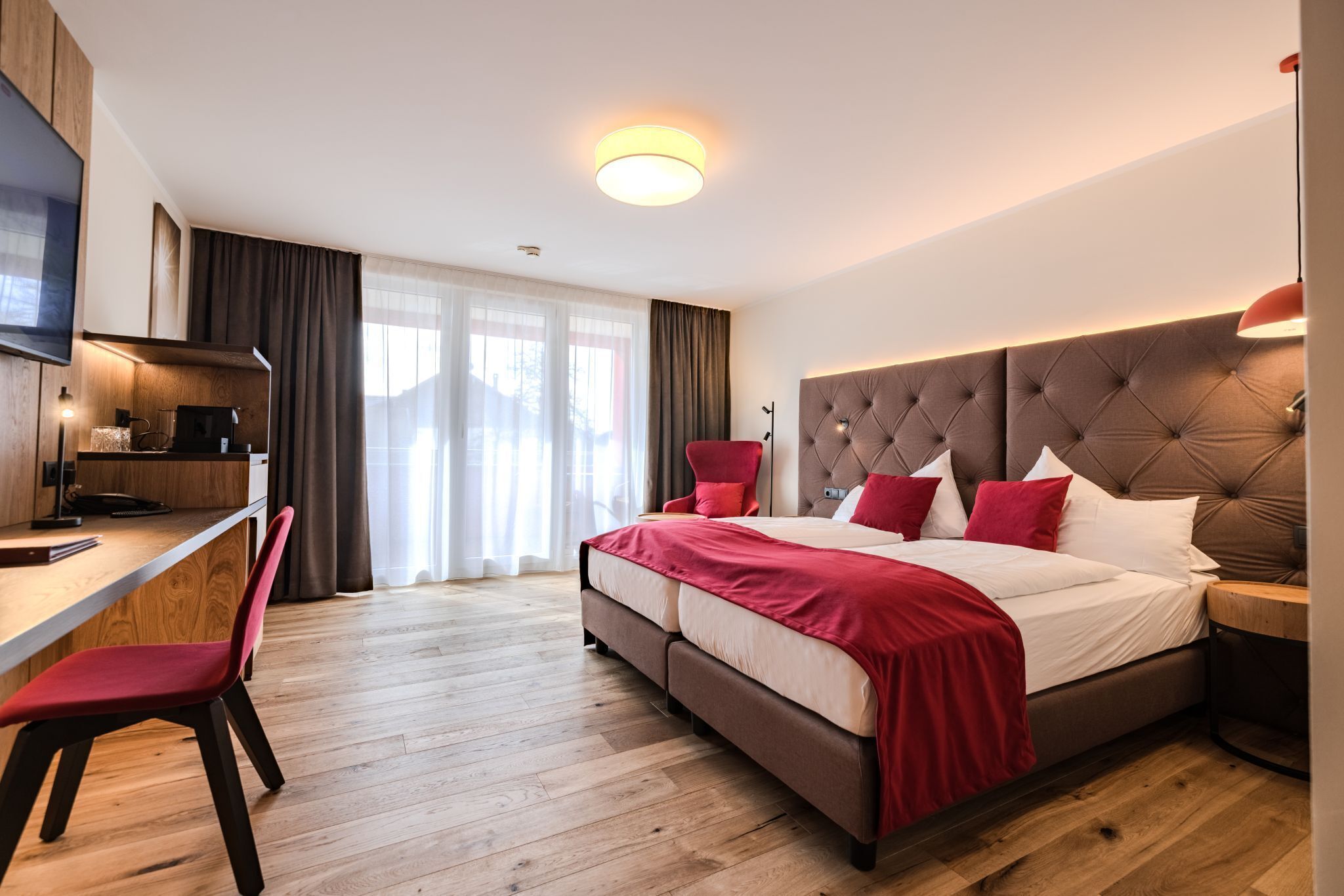 A modern hotel room with a large bed, a desk, and a TV.