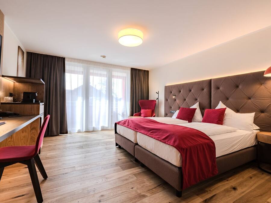 A modern hotel room with a large bed, a desk, and a TV.