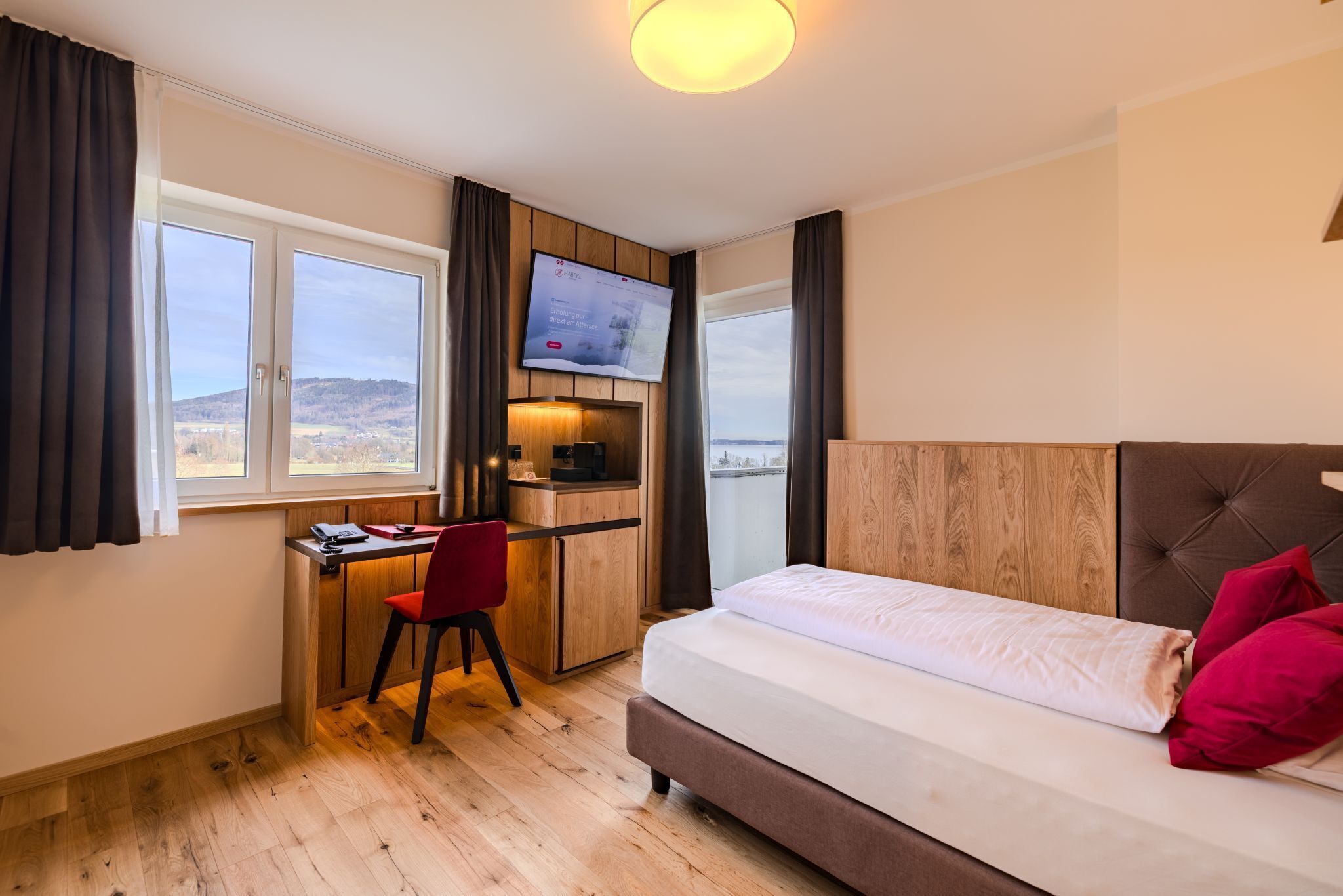 A bedroom with a bed, a desk, and a TV.