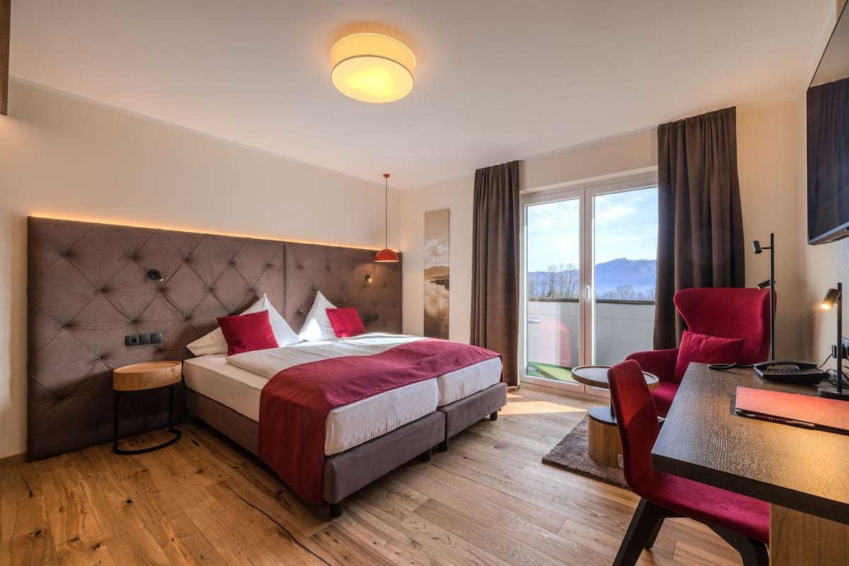 Une chambre d’hôtel moderne, dotée d’un grand lit, d’un bureau, d’une chaise et offrant une vue sur l’extérieur.